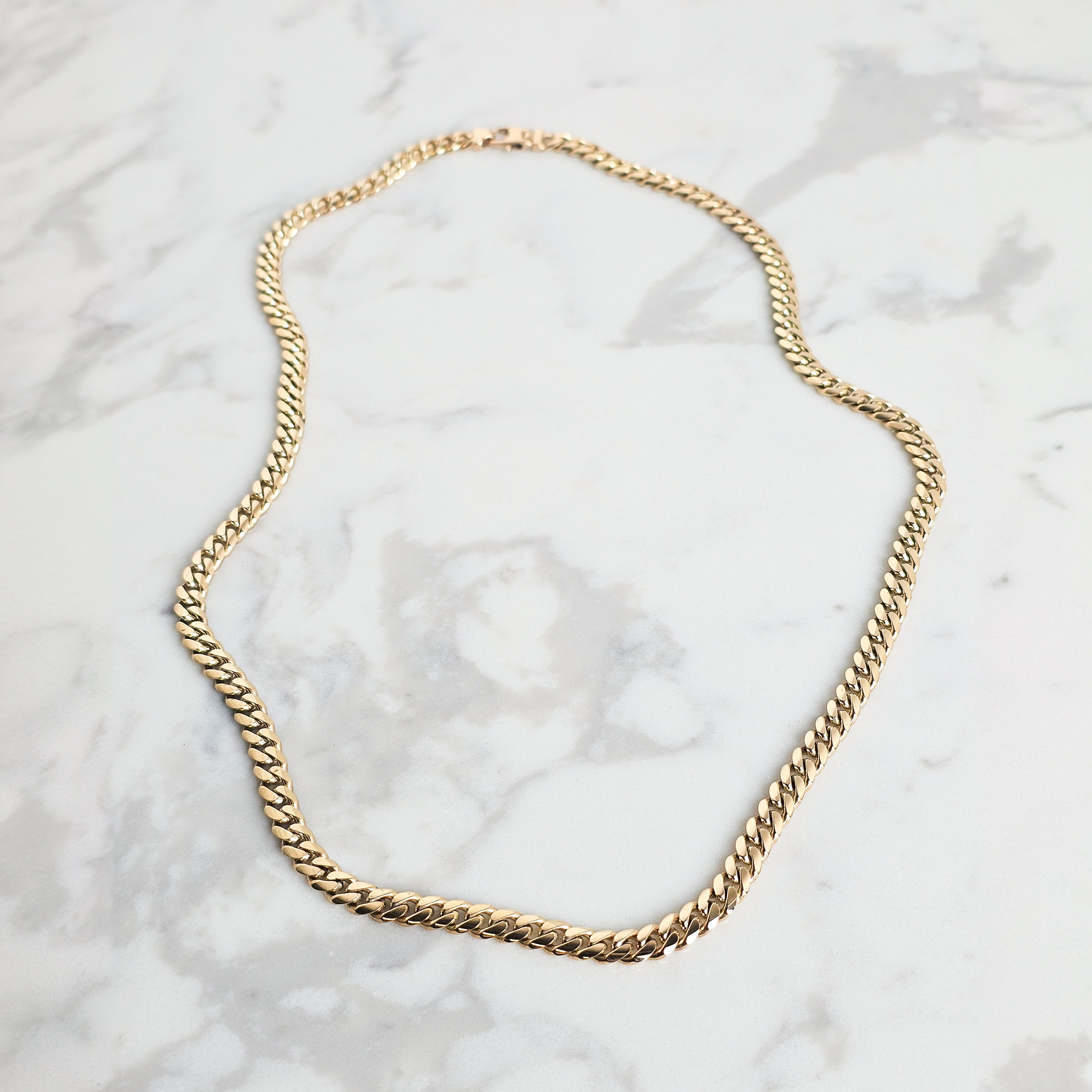 Yellow Gold 6mm handmade cuban mens chain on grey and white marble background