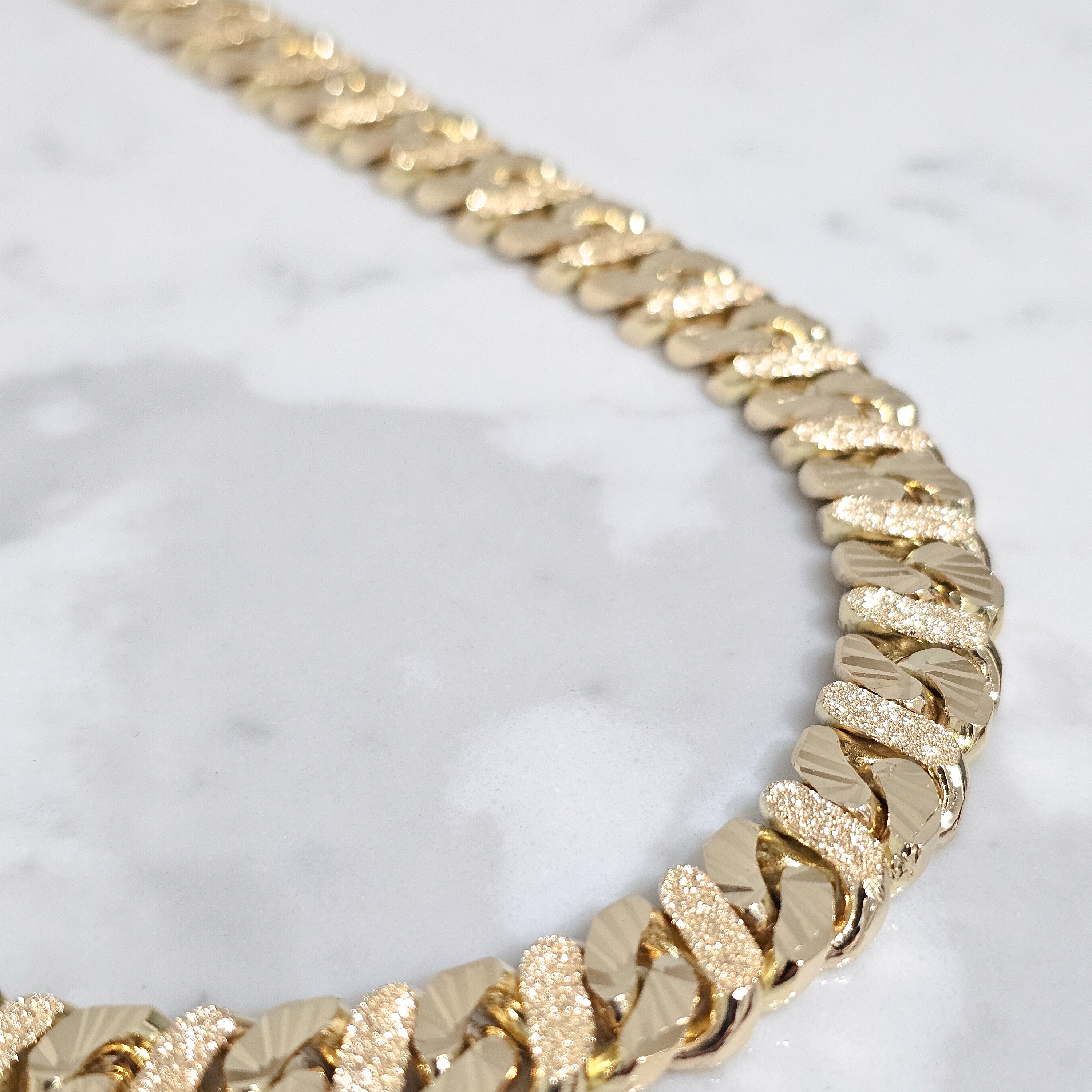 solid yellow mens chain in marble background close up