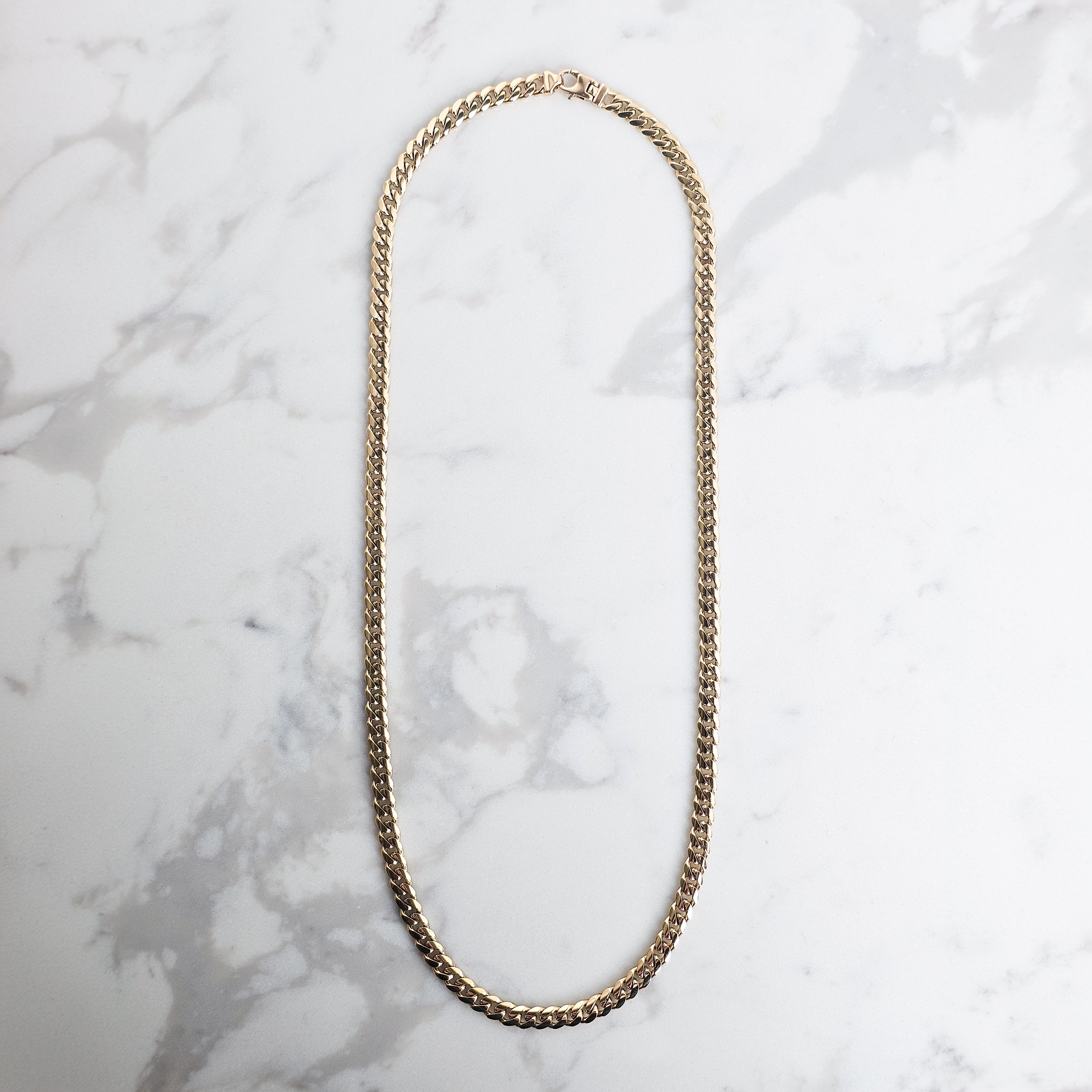 Yellow Gold 6mm handmade cuban mens chain on grey and white marble background
