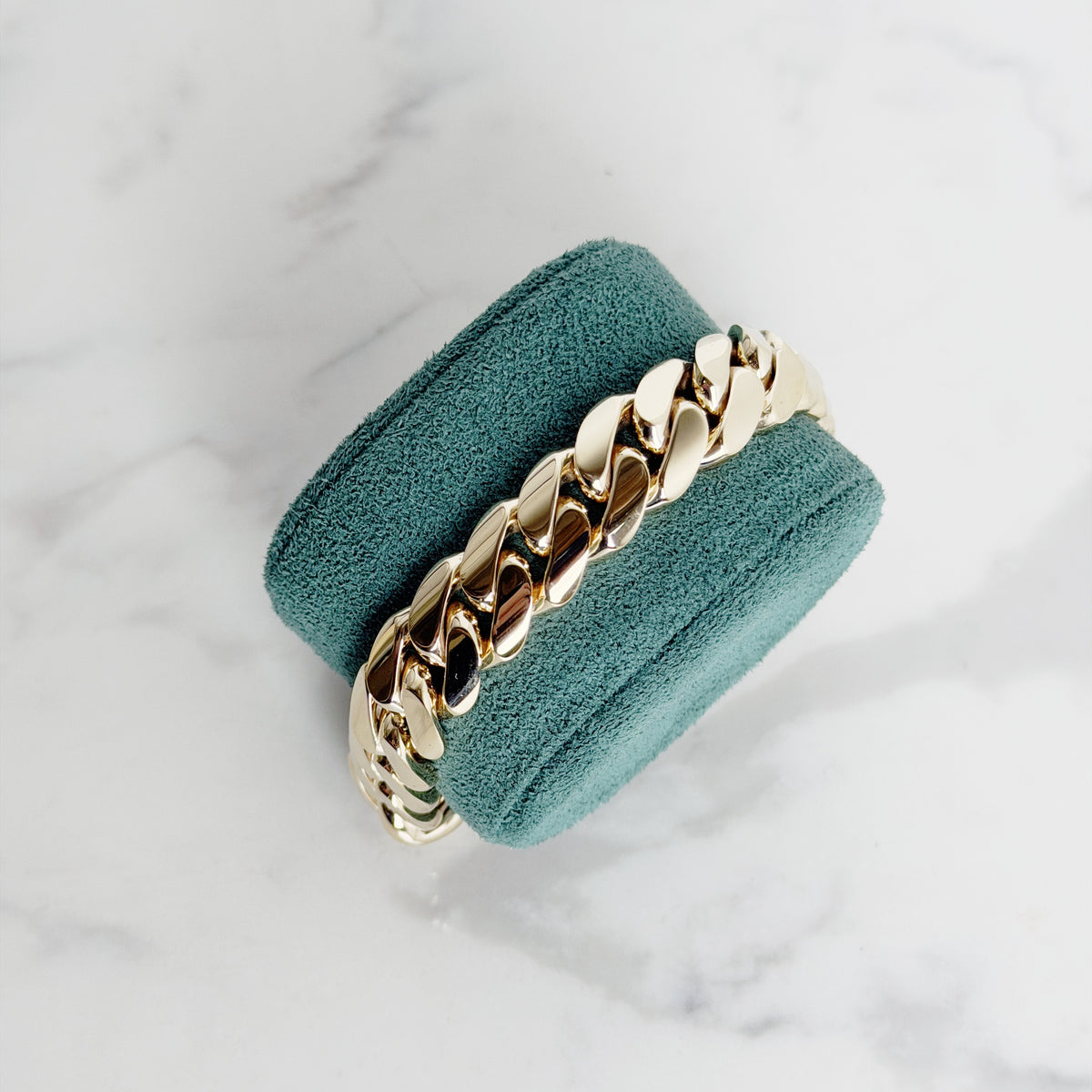 9ct yellow gold 14mm Cuban link bracelet on a green suede stand