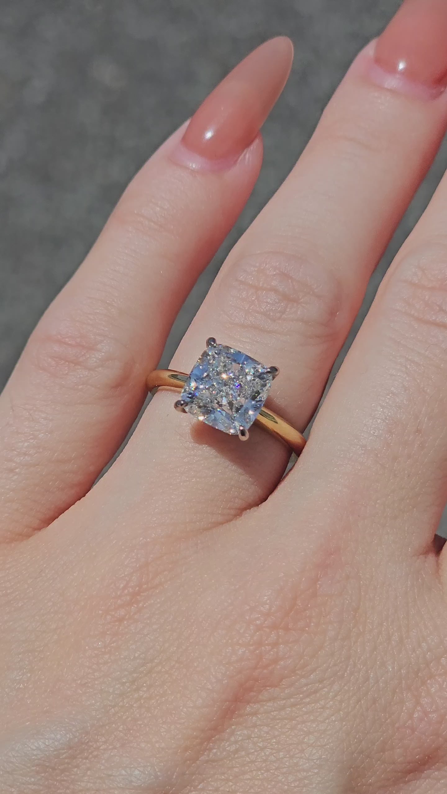 Cushion cut solitaire diamond ring being worn in the sun showing excellent fire and brilliance