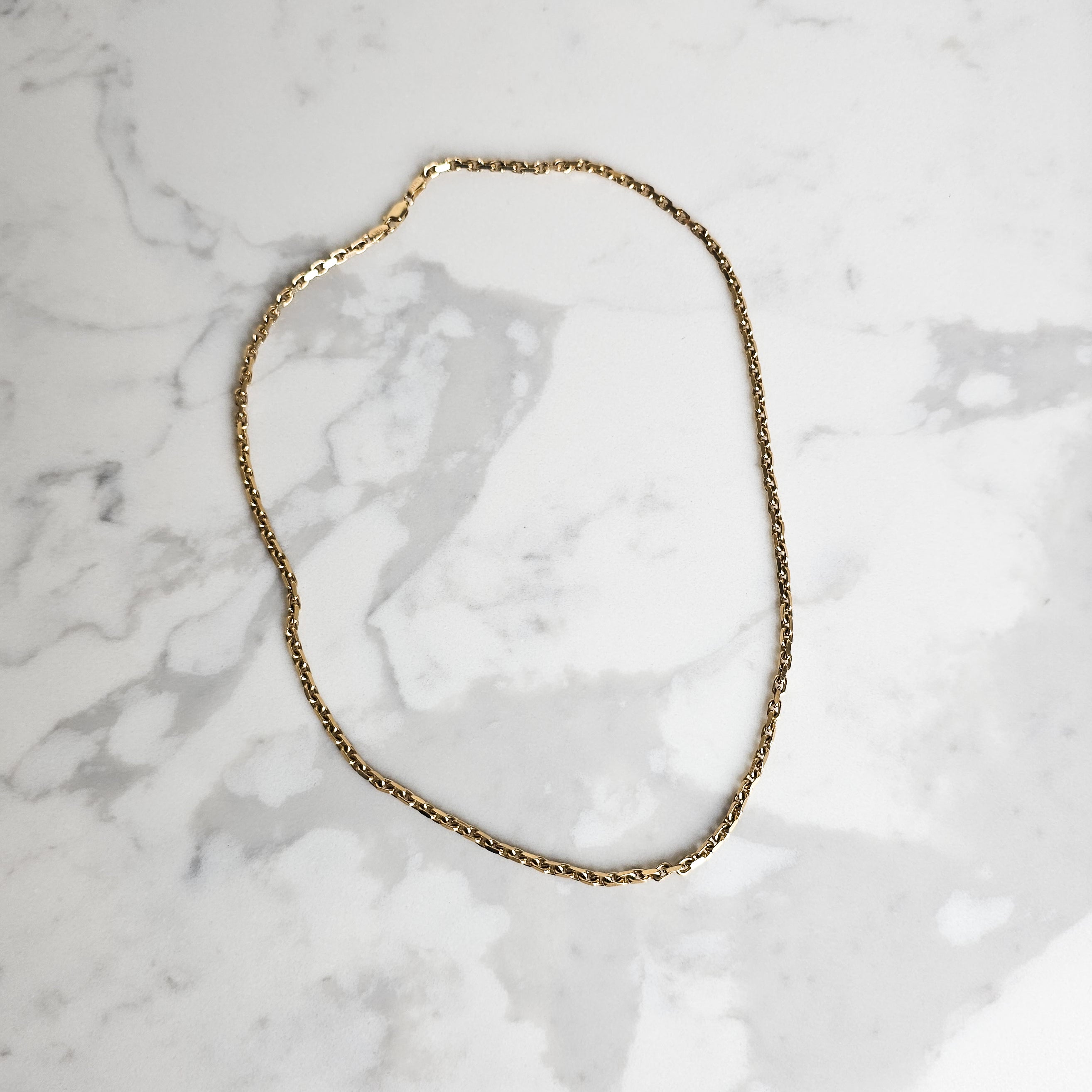 yellow gold Hermes link chain on marble background