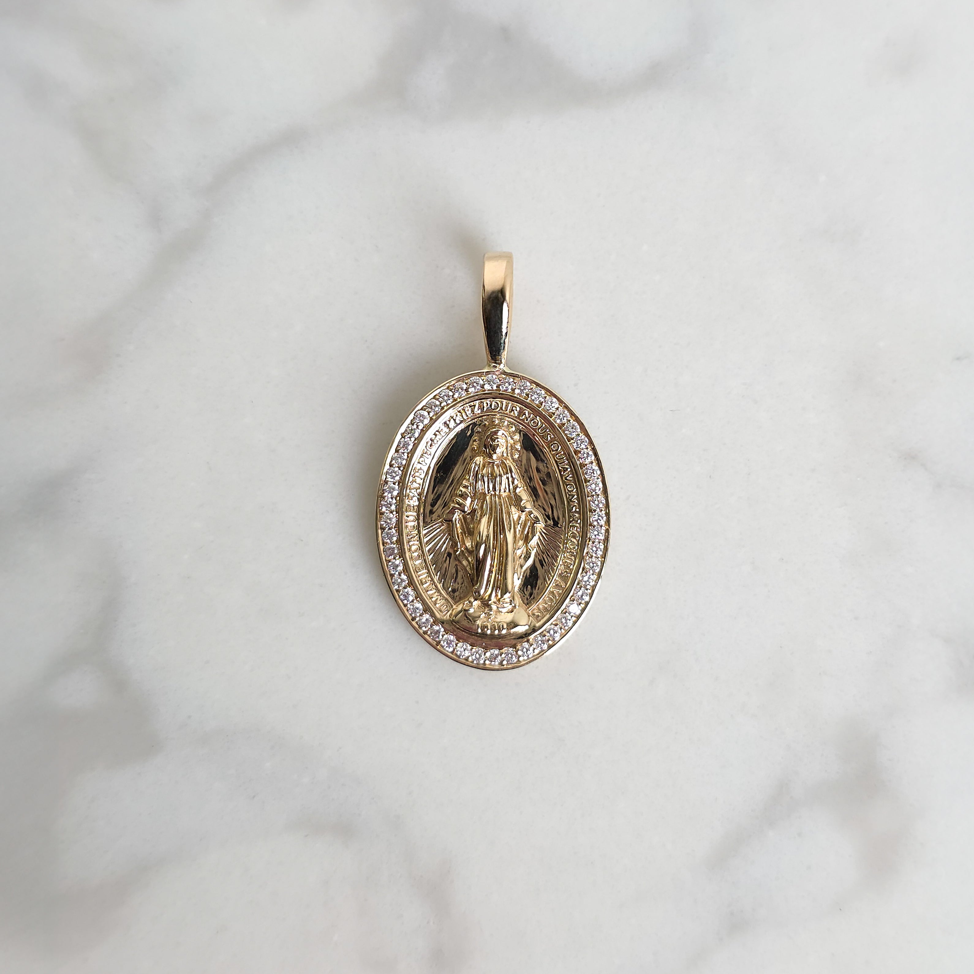 Gold pendant with religious design on a marble surface