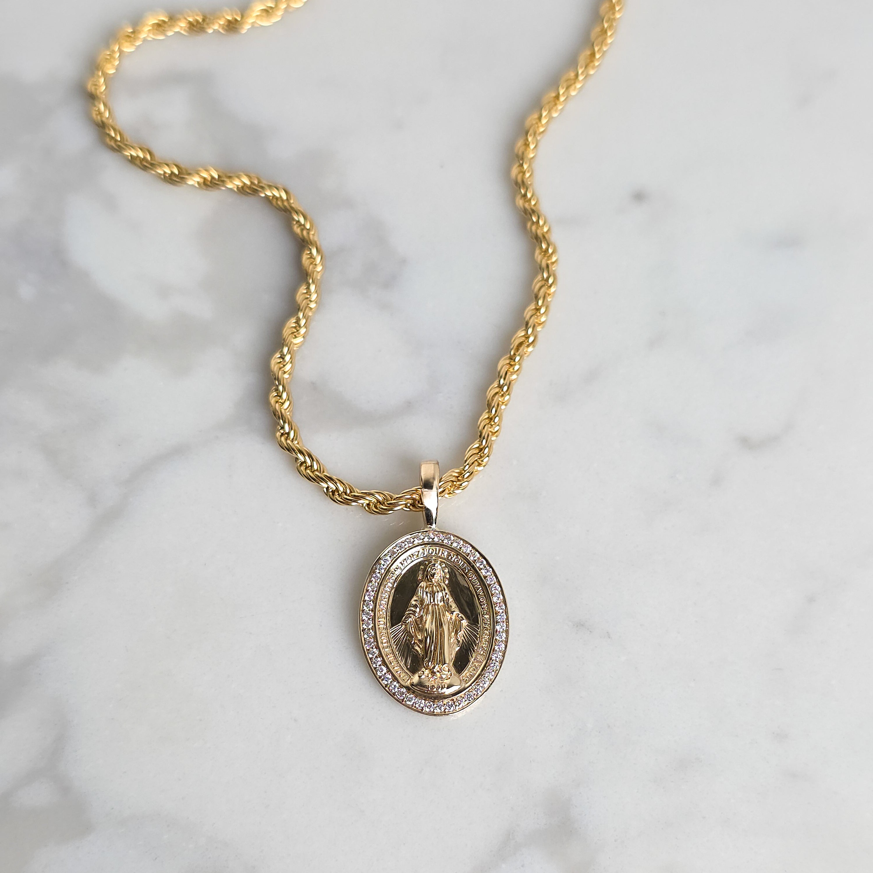 Gold necklace with a pendant on a marble background