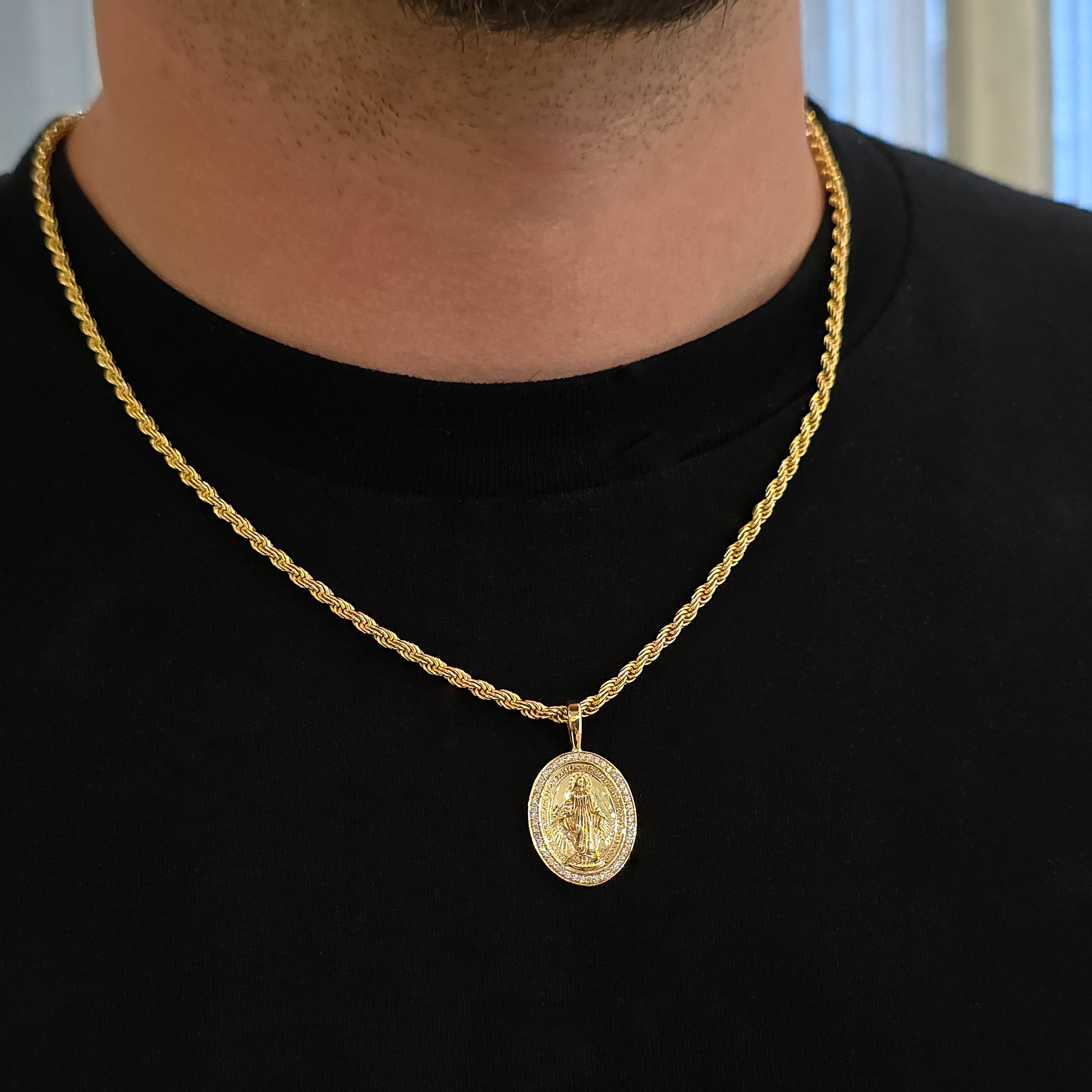 Gold necklace with a pendant worn by a person against a neutral background