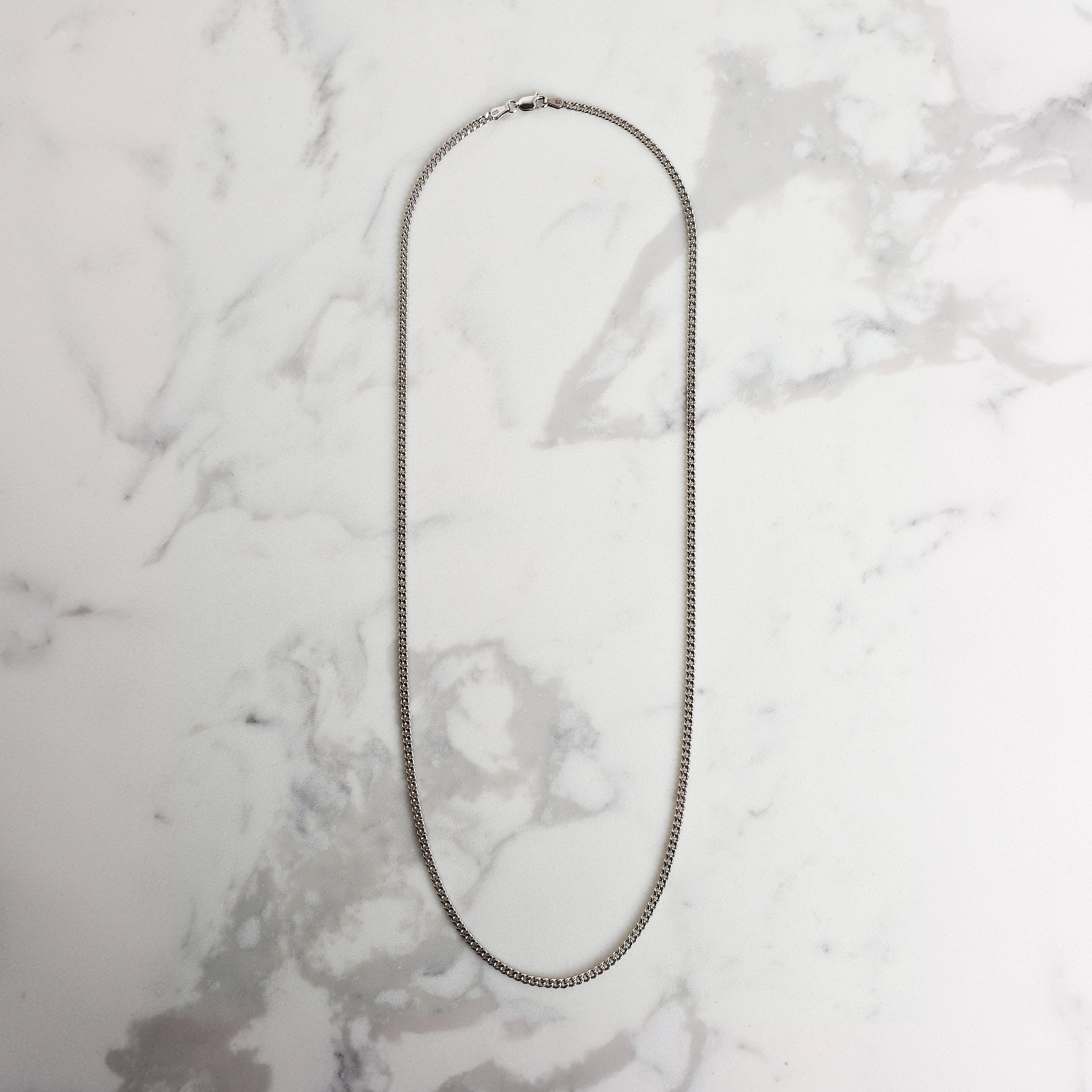 White gold mens chain on marble background 