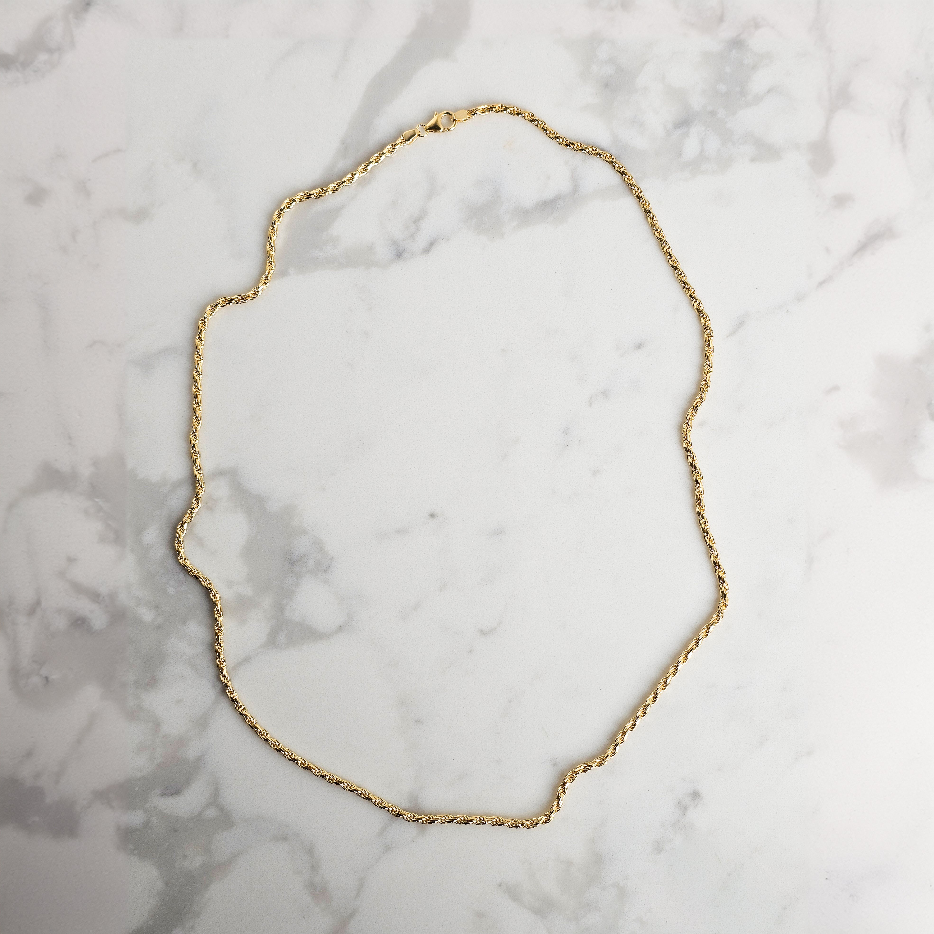 yellow gold rope chain on marble background