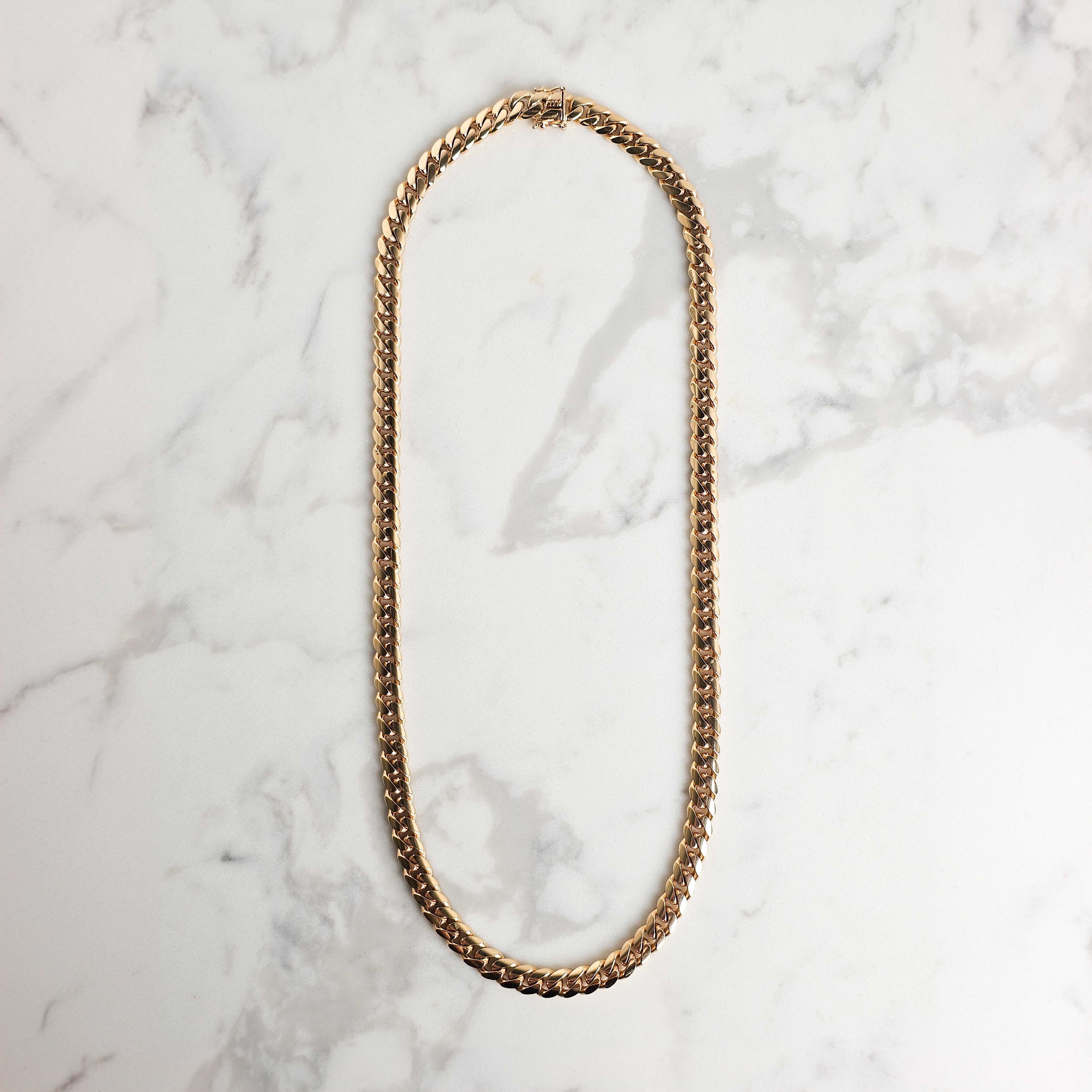 cuban chain hanging on marble background 