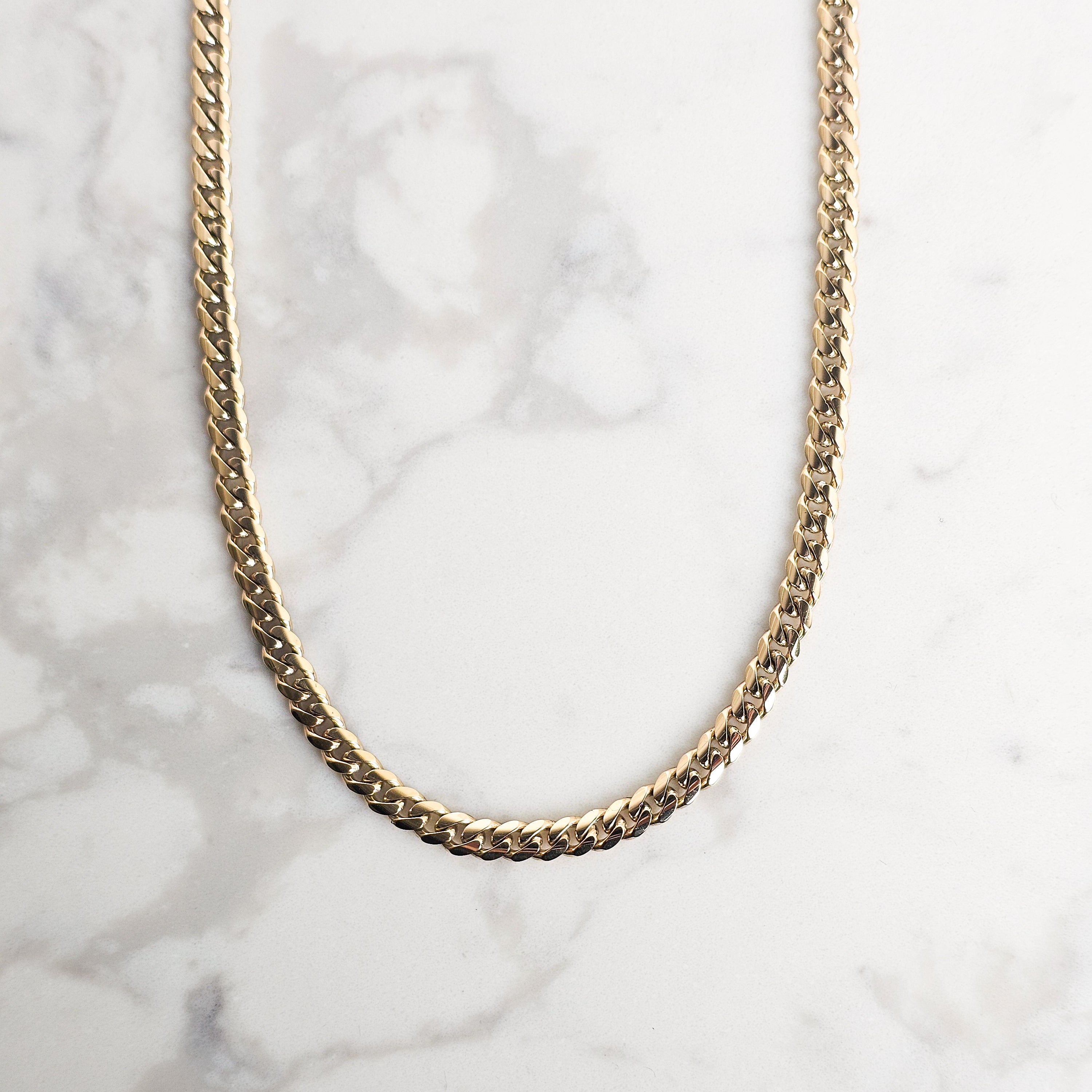 Yellow Gold 6mm handmade cuban mens chain on grey and white marble background